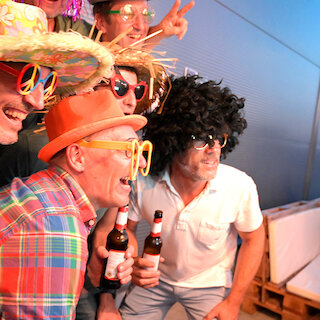 Verkleidete Menschen mit Getränken in der Hand lachen für ein Foto