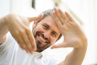 Mann formt Raute mit den Händen und lacht