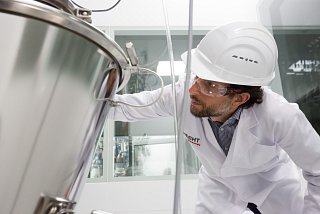 Mann in Schutzkleidung begutachtet technische Anlage